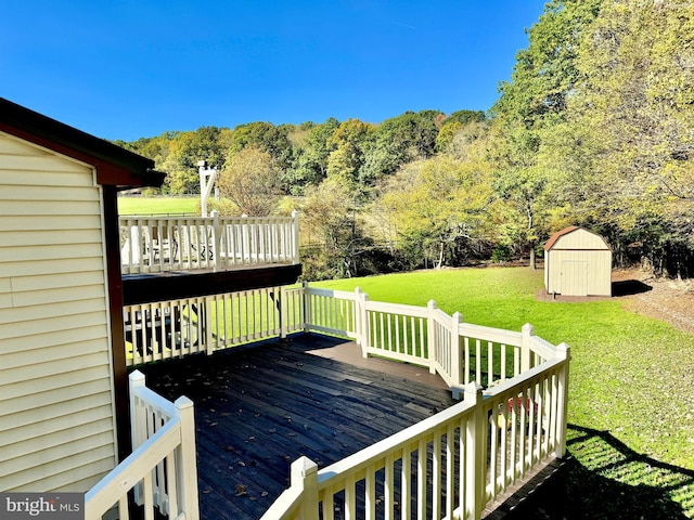 wooden terrace featuring an outbuilding, a storage unit, a forest view, and a yard