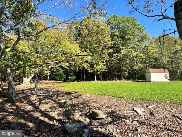 view of yard with a wooded view, an outdoor structure, and a shed