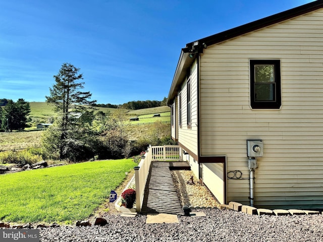 view of side of home featuring a yard, a garage, and a rural view