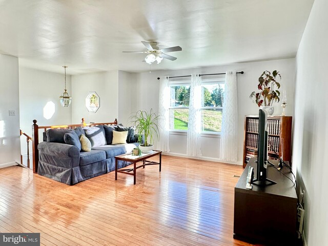 living room featuring light wood finished floors, ceiling fan, and baseboards