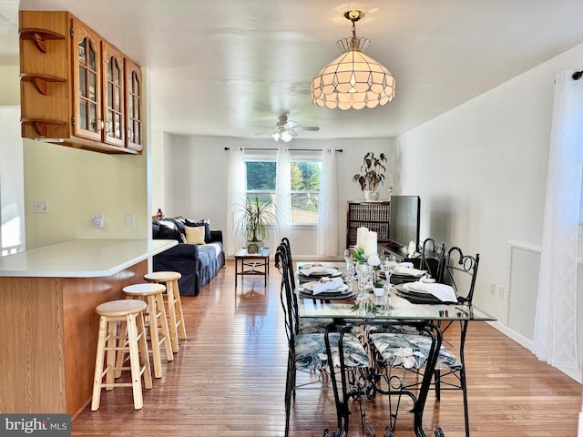 dining area with light wood finished floors, ceiling fan, and baseboards