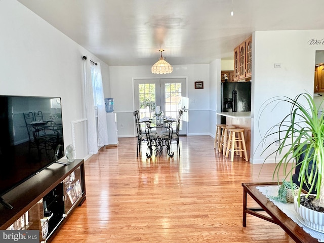 dining area with french doors, light wood-type flooring, and baseboards