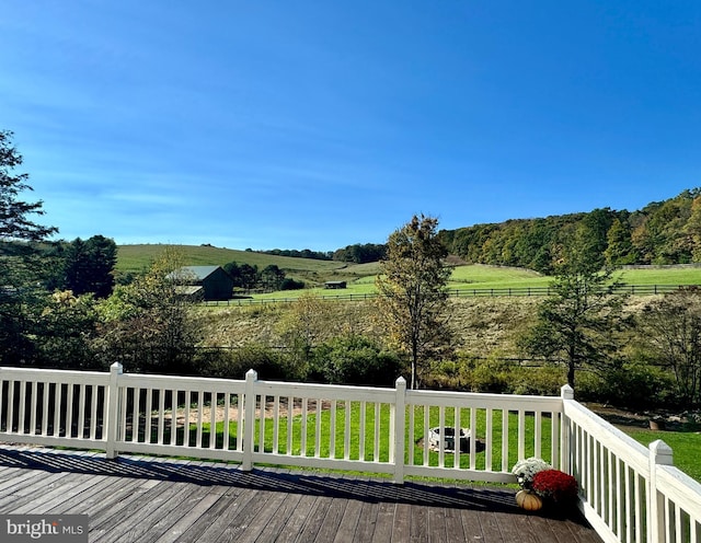 wooden deck with a rural view and a yard