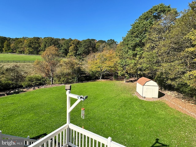 view of yard featuring a forest view, an outbuilding, and a storage unit