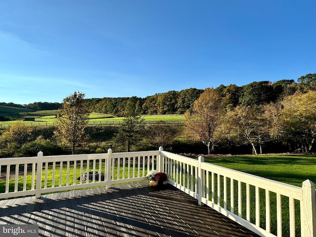 wooden deck with a rural view and a lawn