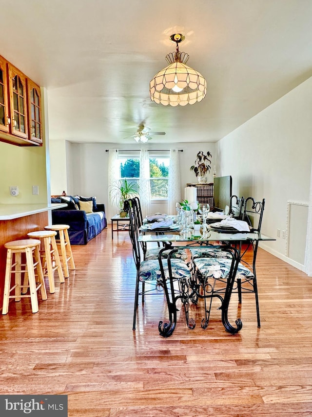 dining space with light wood-type flooring, ceiling fan, and baseboards