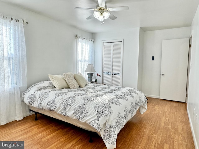 bedroom featuring light wood-type flooring, ceiling fan, and a closet