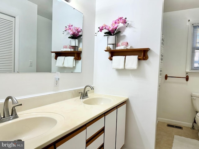 full bath with a sink, visible vents, toilet, and double vanity