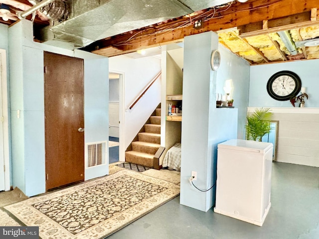 unfinished basement with visible vents and stairway