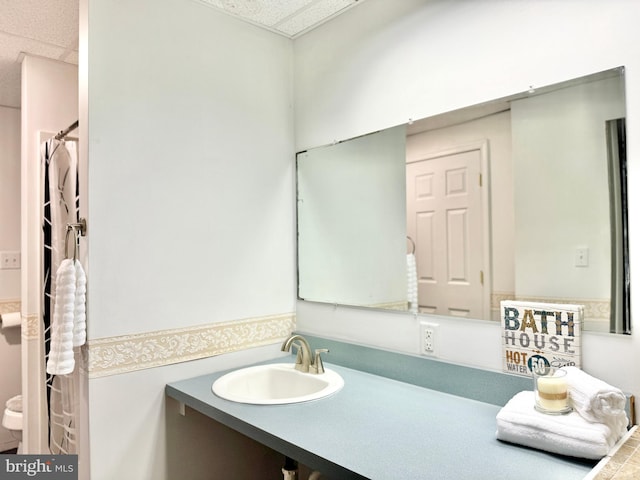 bathroom featuring a paneled ceiling and vanity