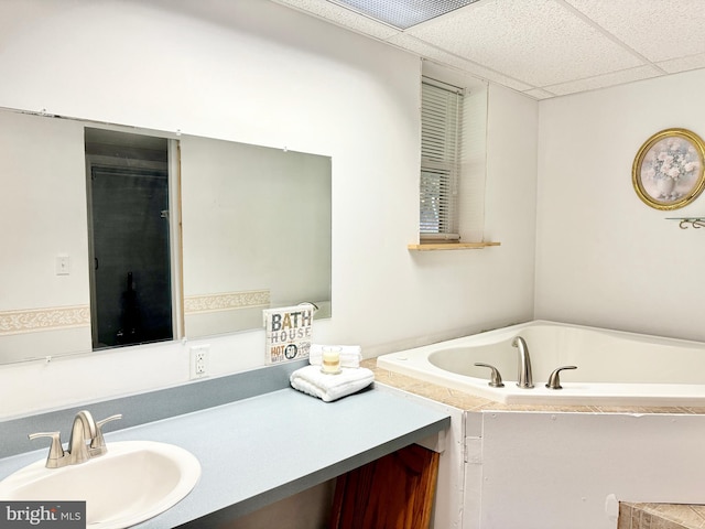 bathroom with a drop ceiling, vanity, and a bathing tub