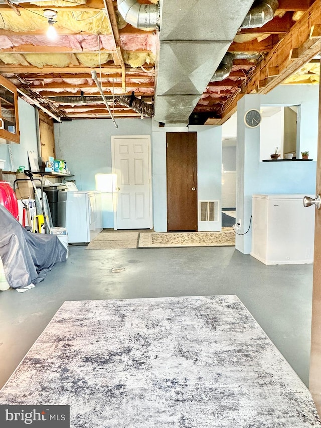unfinished below grade area featuring washer and dryer and visible vents