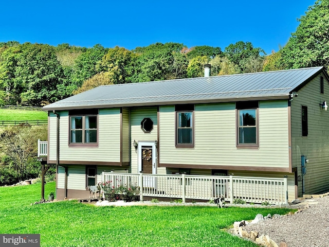 split foyer home featuring metal roof, a front yard, and a standing seam roof