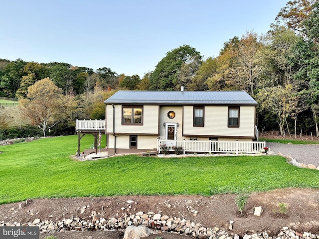 raised ranch featuring a patio, metal roof, and a front lawn