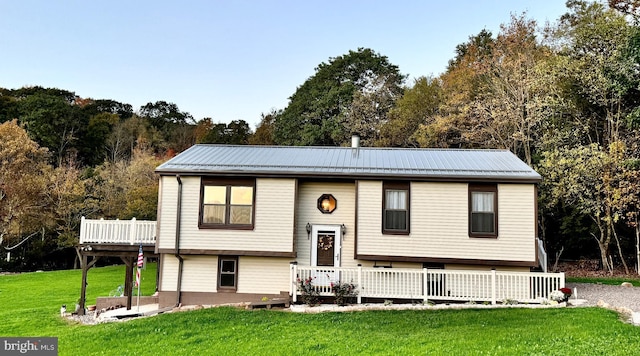 raised ranch featuring a wooden deck and a front lawn