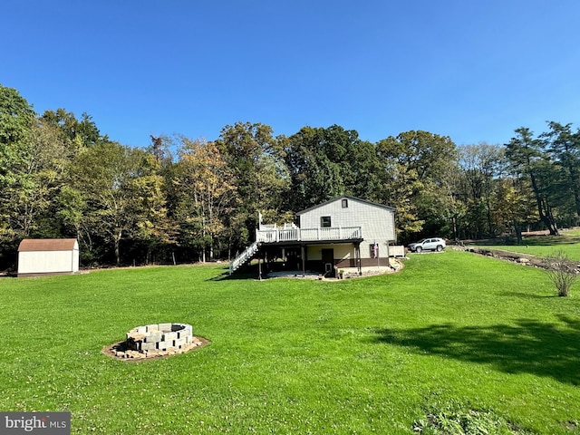 view of yard featuring a shed, an outdoor structure, stairway, an outdoor fire pit, and a deck