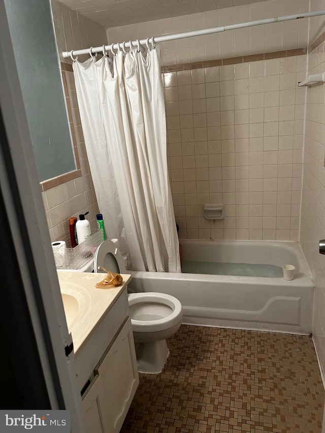 full bathroom featuring toilet, vanity, shower / bath combination with curtain, and tile walls