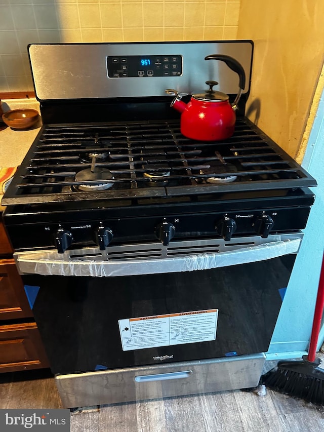 details featuring decorative backsplash, stainless steel range, and dark wood-type flooring