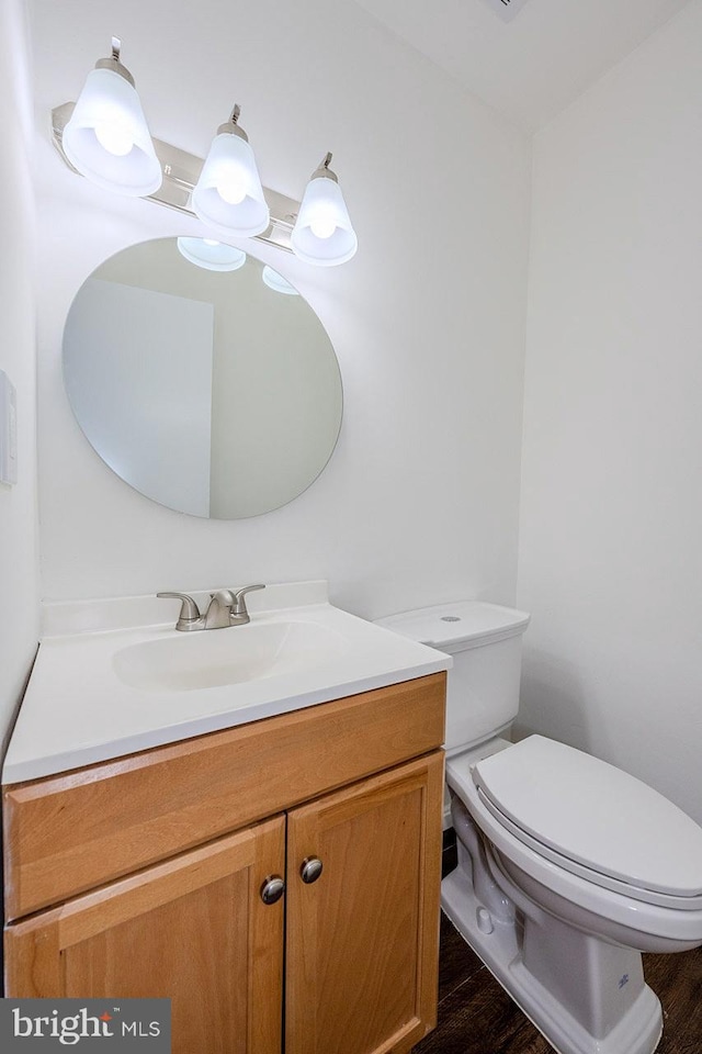 bathroom with hardwood / wood-style floors, vanity, and toilet