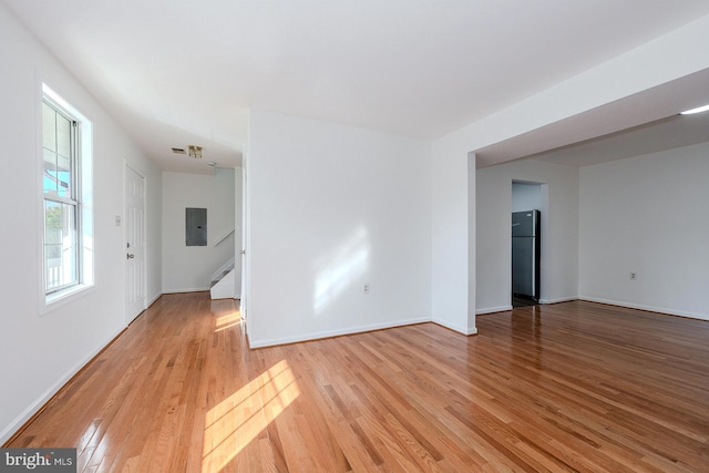 unfurnished room featuring electric panel and light hardwood / wood-style floors