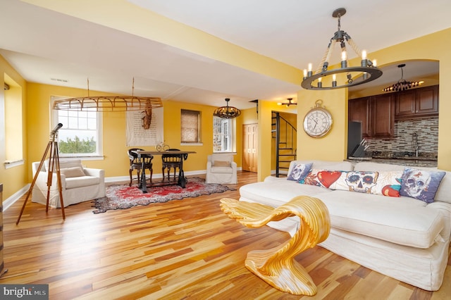 living room with an inviting chandelier, light hardwood / wood-style flooring, and sink