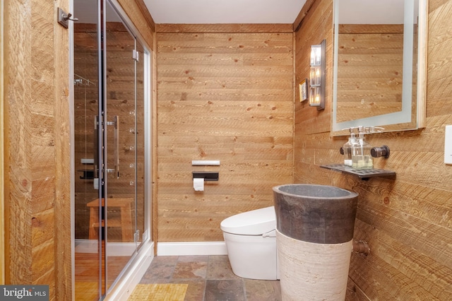 bathroom with a shower with shower door, wood walls, and toilet