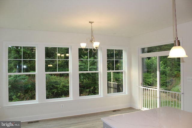 unfurnished dining area with a notable chandelier, hardwood / wood-style flooring, and plenty of natural light