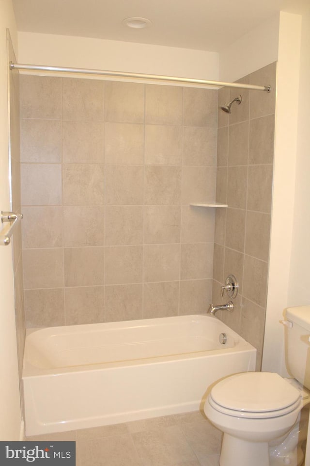 bathroom featuring tiled shower / bath, tile patterned flooring, and toilet