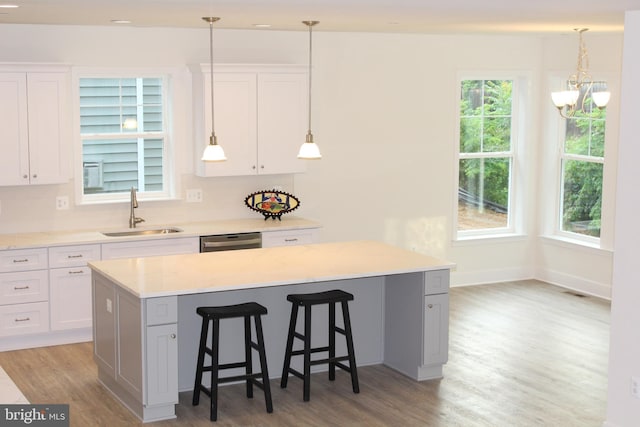 kitchen featuring a wealth of natural light, white cabinetry, a center island, and sink