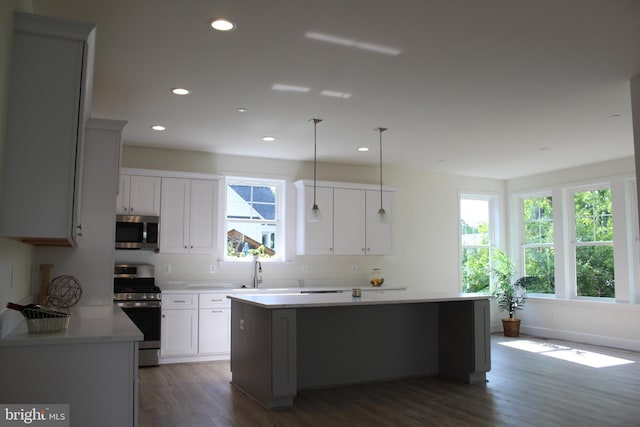 kitchen featuring a center island, appliances with stainless steel finishes, white cabinetry, and dark wood-type flooring