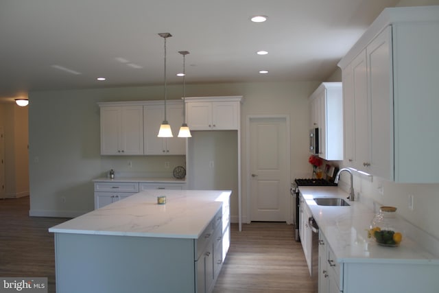 kitchen with light hardwood / wood-style floors, white cabinets, pendant lighting, a center island, and sink