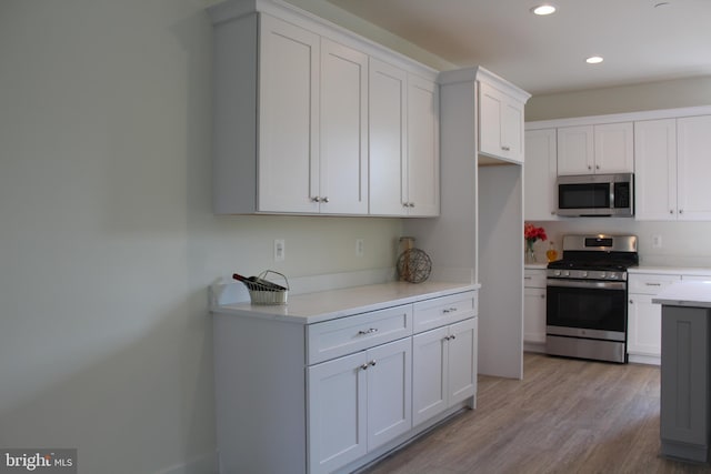 kitchen with white cabinets, stainless steel appliances, and light hardwood / wood-style floors