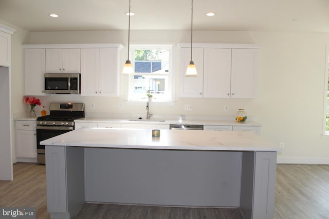 kitchen featuring pendant lighting, sink, white cabinetry, appliances with stainless steel finishes, and hardwood / wood-style floors