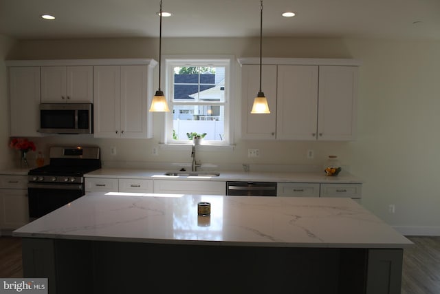 kitchen featuring stainless steel appliances, white cabinetry, a center island, and sink