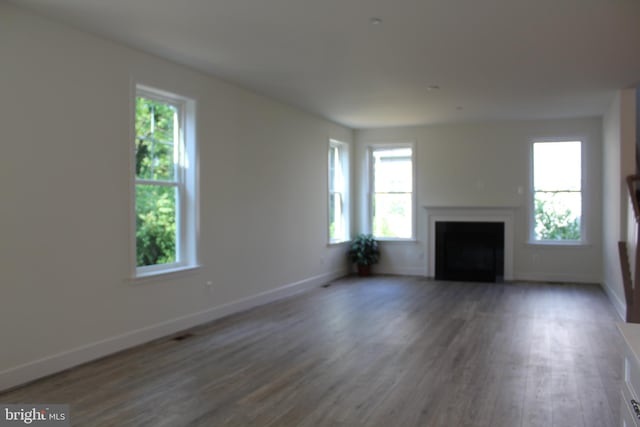 unfurnished living room with dark wood-type flooring and a wealth of natural light