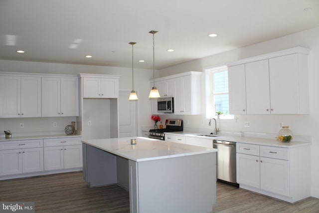 kitchen with sink, decorative light fixtures, white cabinetry, appliances with stainless steel finishes, and a center island