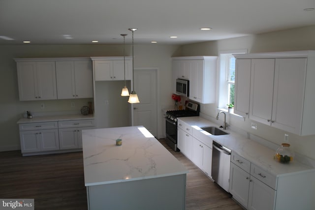 kitchen featuring decorative light fixtures, a kitchen island, appliances with stainless steel finishes, and white cabinetry