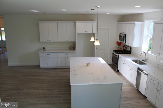 kitchen with appliances with stainless steel finishes, white cabinetry, sink, and decorative light fixtures