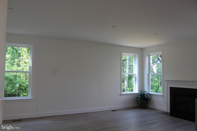 unfurnished living room featuring a wealth of natural light and dark wood-type flooring