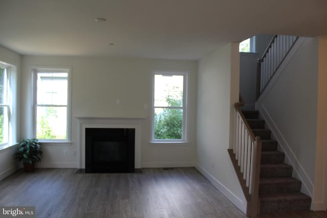 unfurnished living room with dark wood-type flooring and a wealth of natural light