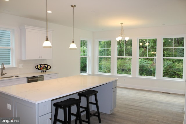 kitchen featuring dishwasher, light hardwood / wood-style floors, sink, white cabinets, and a kitchen island