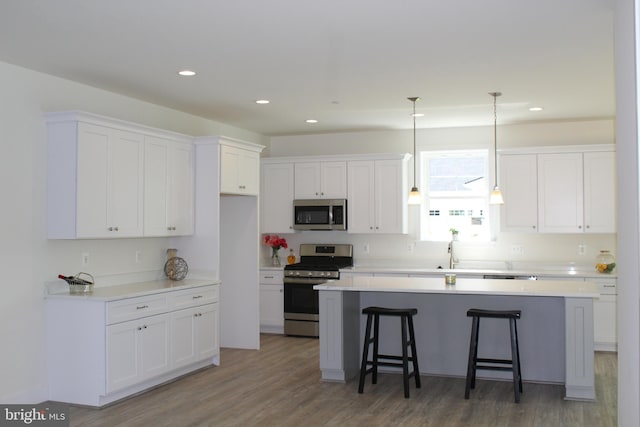 kitchen featuring appliances with stainless steel finishes, a kitchen island, dark hardwood / wood-style flooring, and white cabinets