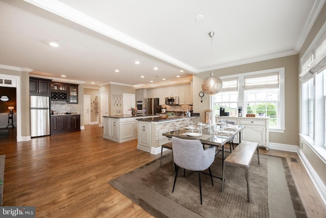 dining area with crown molding, hardwood / wood-style floors, and sink