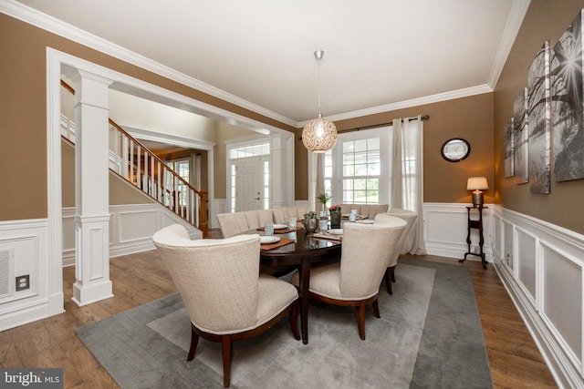 dining space featuring an inviting chandelier, crown molding, dark hardwood / wood-style floors, and ornate columns