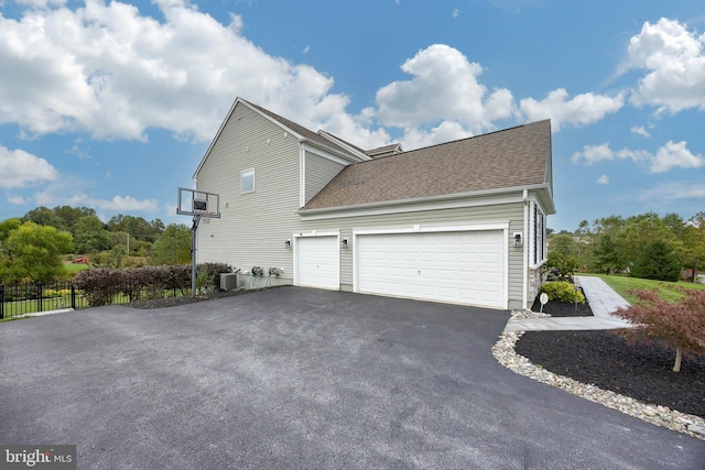 view of side of home with a garage and central AC