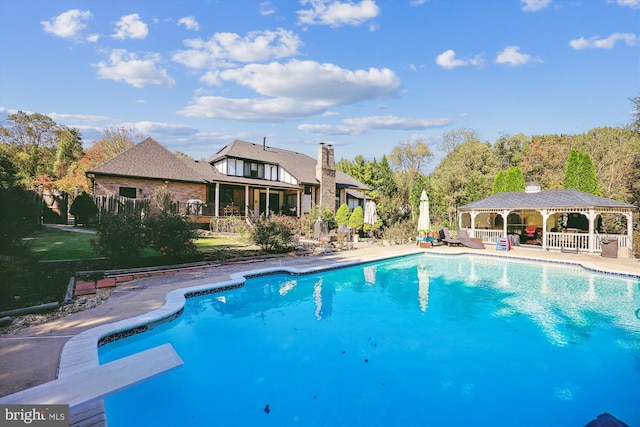 view of swimming pool featuring a diving board, a patio area, and a gazebo