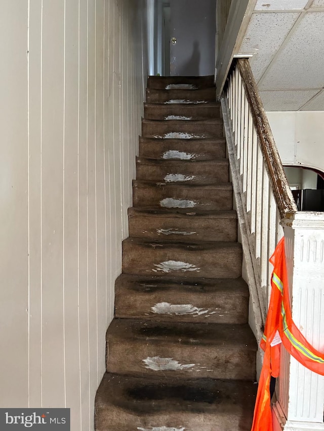 stairway featuring a drop ceiling