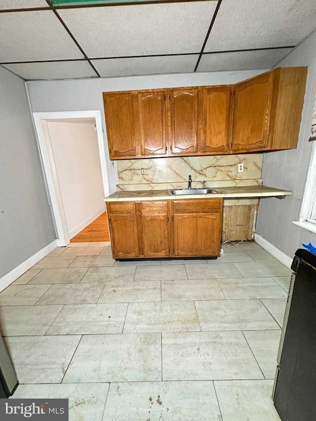 kitchen featuring a paneled ceiling, backsplash, and sink