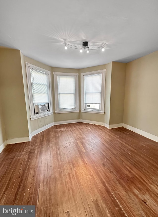 spare room featuring cooling unit, ceiling fan, and hardwood / wood-style flooring