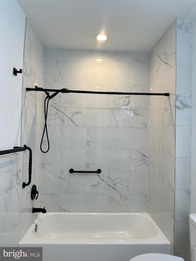 bathroom with tiled shower / bath combo and toilet